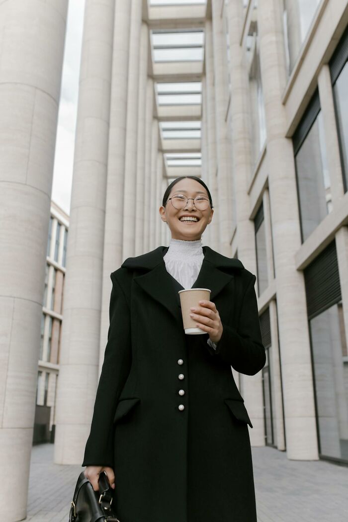 Smiling female lawyer holding coffee outside courthouse columns