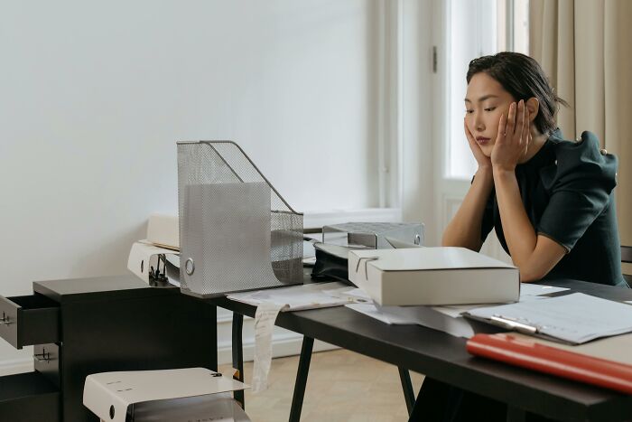 Stressed woman at cluttered desk depicting work pressure stress and peace over paycheck