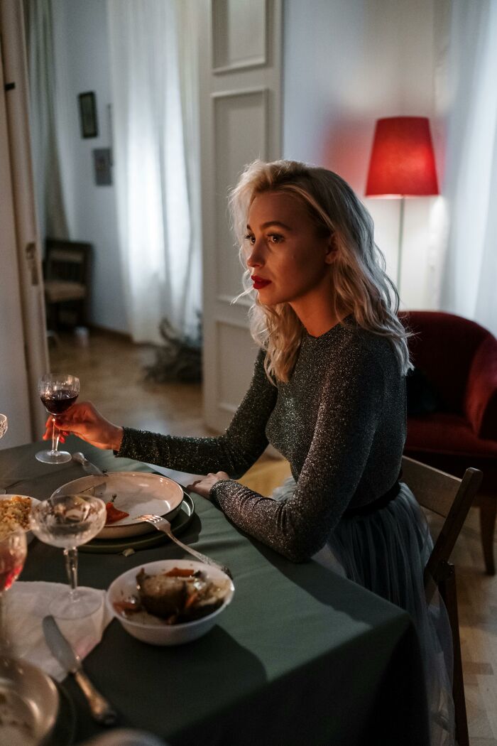 Woman thoughtfully drinking wine with weird confessions ambiance