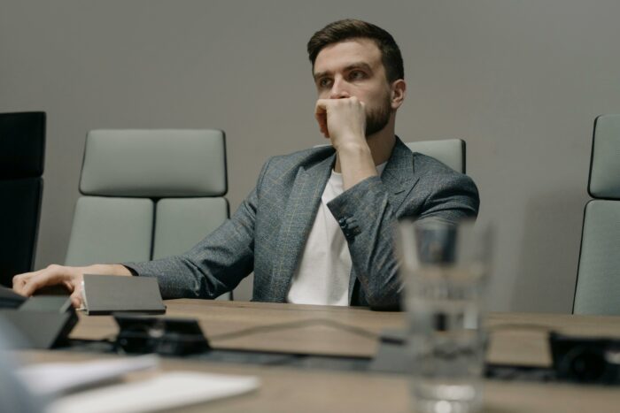 Man in suit sitting thoughtfully in office chair during interview Man in suit sitting thoughtfully in office chair during interview