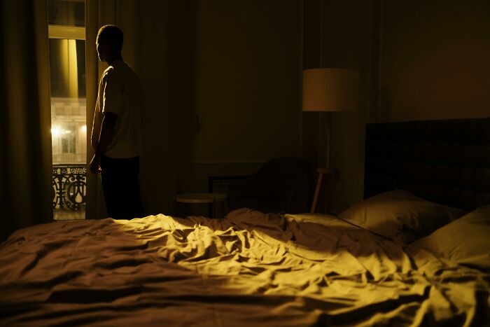 Person standing alone in dimly lit bedroom at night