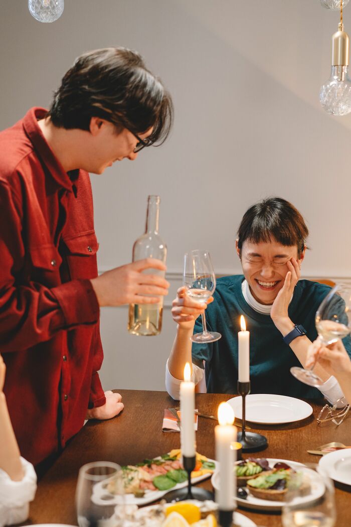 People enjoying dinner and laughing with wine at candlelit table