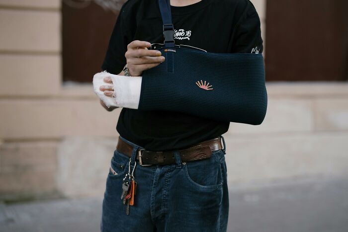 A person with a bandaged hand and arm in a sling, showcasing resilient patients who are still alive.