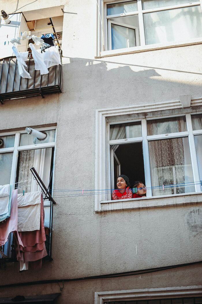 Neighbors from hell looking through apartment window with laundry hanging nearby