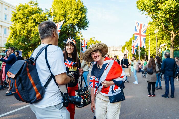 People in British attire on a street with Union Jack flags, enjoying a gathering related to British vocabulary.
