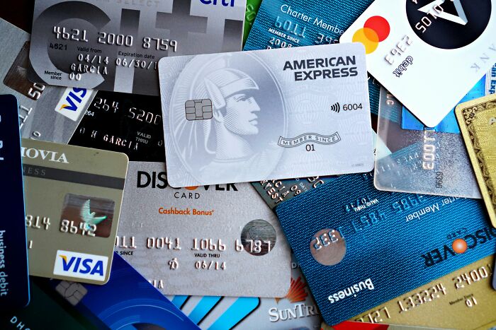 A pile of various credit and debit cards, including American Express, Visa, and Discover, illustrating expensive habits.