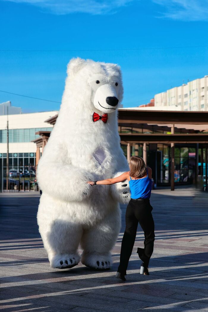 Person in white bear costume holding hands with woman in black pants outside