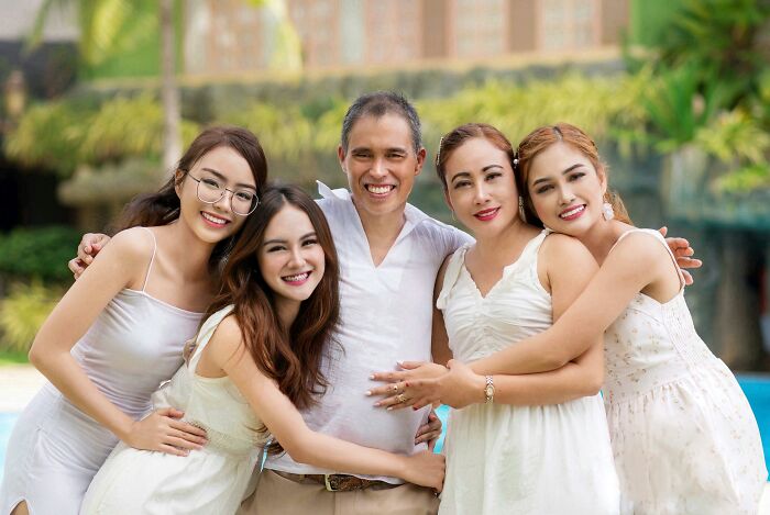 Smiling man with four daughters standing close and happy outdoors