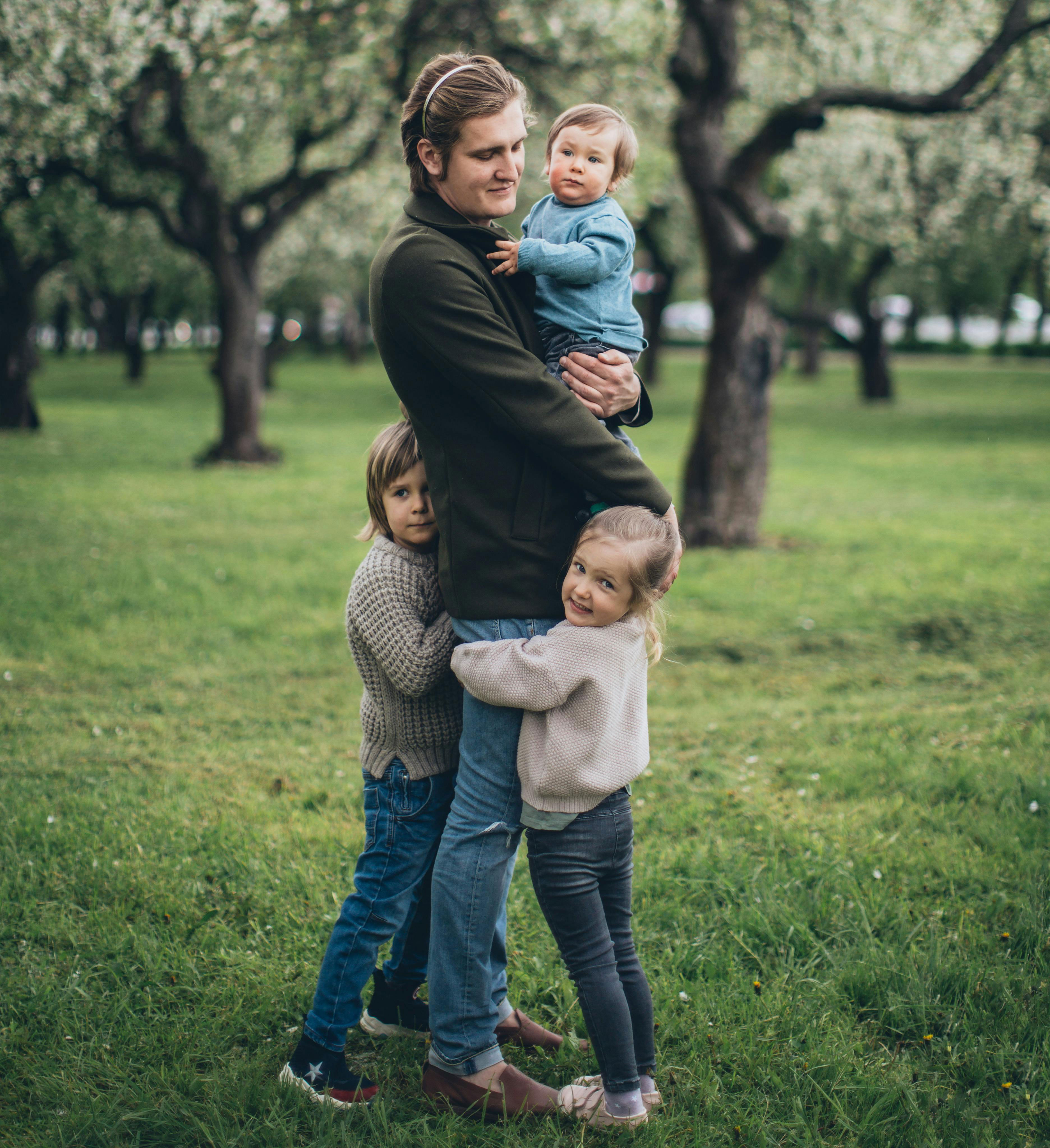 Brother holding four kids in a park showing family challenges with multiple children