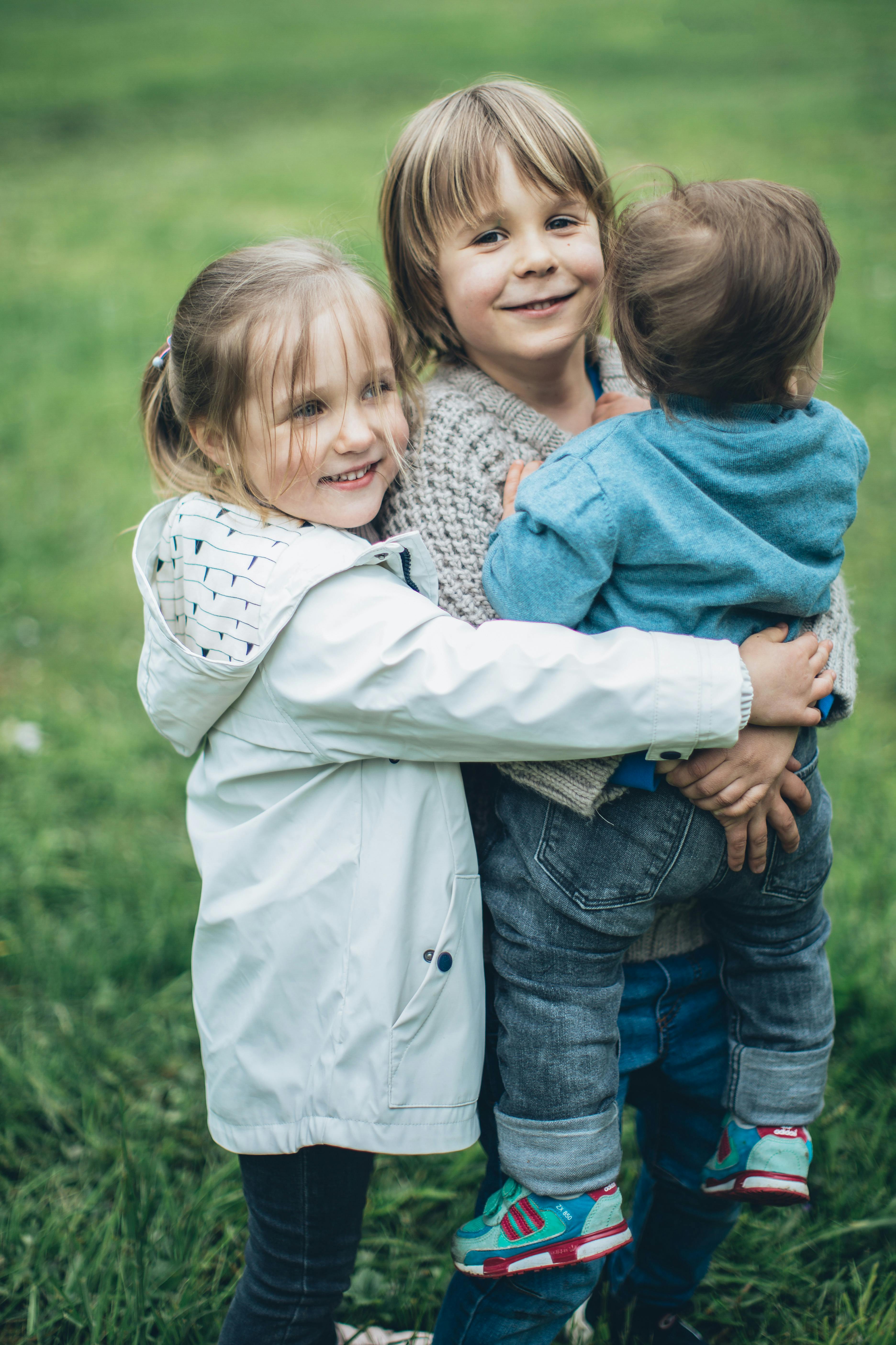 Three children hugging outdoors representing brother's kids