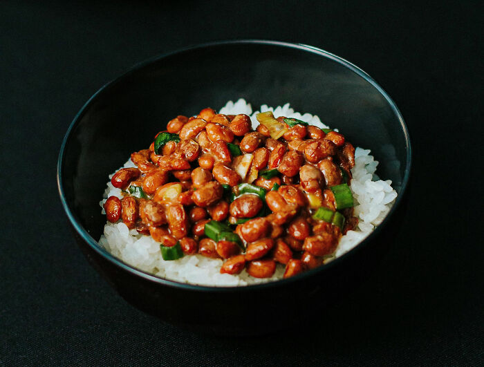 Bowl of rice topped with beans and green onions as a cheap poverty meal