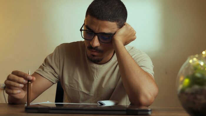 Man looking thoughtful holding pen at desk related to proposal dilemma