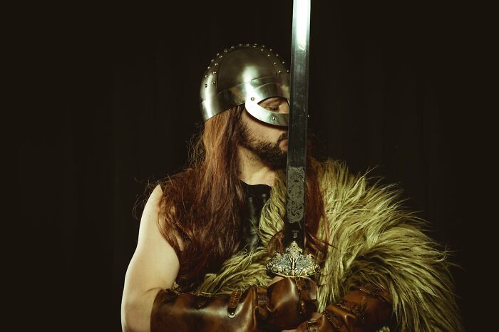 Viking warrior holding sword with metal helmet and fur cloak