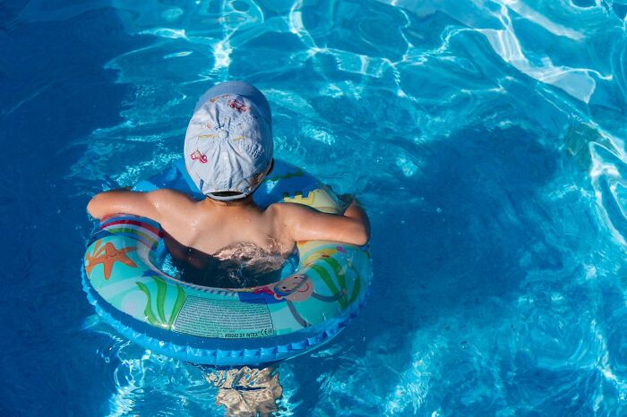 Child floating in pool using inflatable ring
