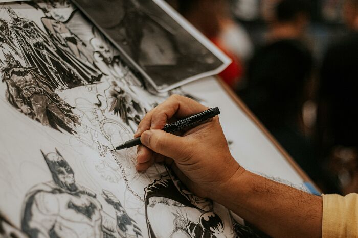 Artist drawing detailed fan art of iconic movie characters including superheroes with black ink pen Artist drawing detailed fan art of iconic movie characters including superheroes with black ink pen