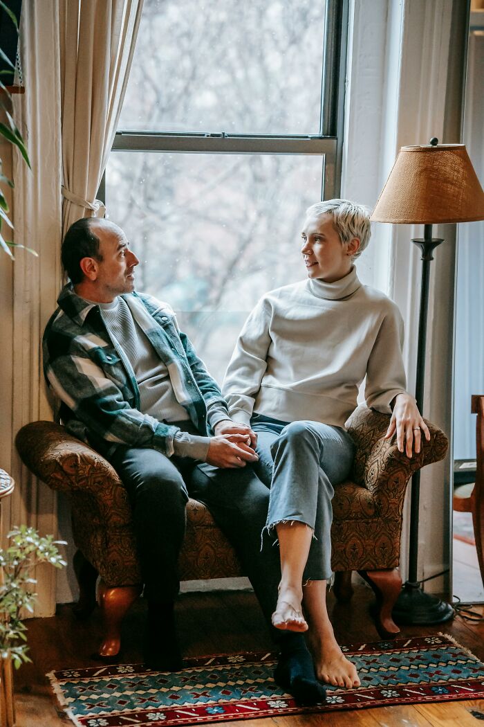 Couple holding hands talking on a vintage couch in a cozy room