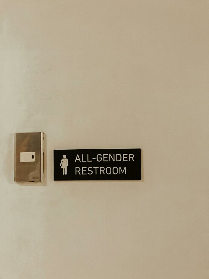 Sign on beige wall indicating all-gender restroom access