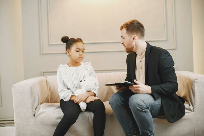 Man counseling a girl holding a teddy bear about cult experiences
