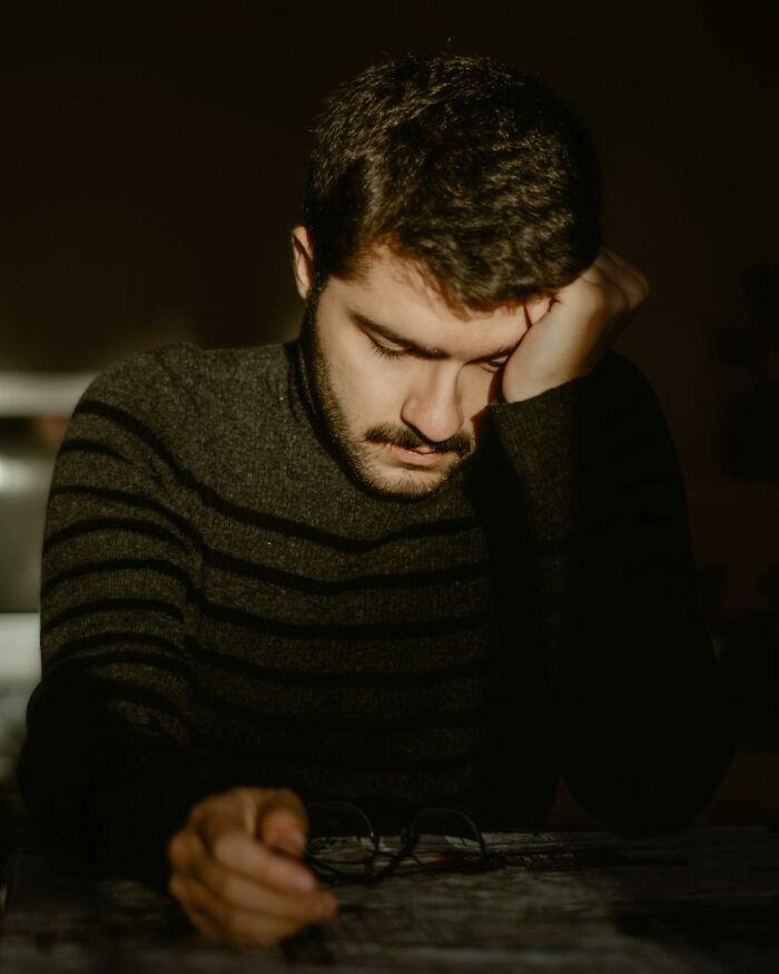 A man with a beard leaning on his hand, looking down thoughtfully, possibly contemplating wedding drama.
