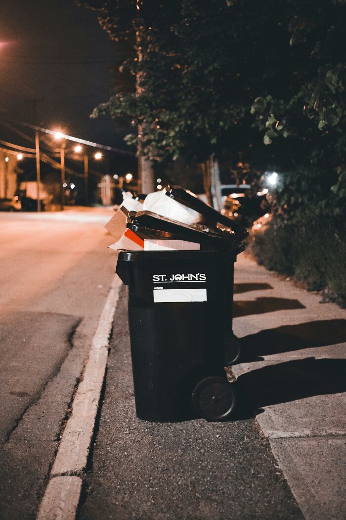 Overflowing trash bin on sidewalk causing neighborhood nuisance at night