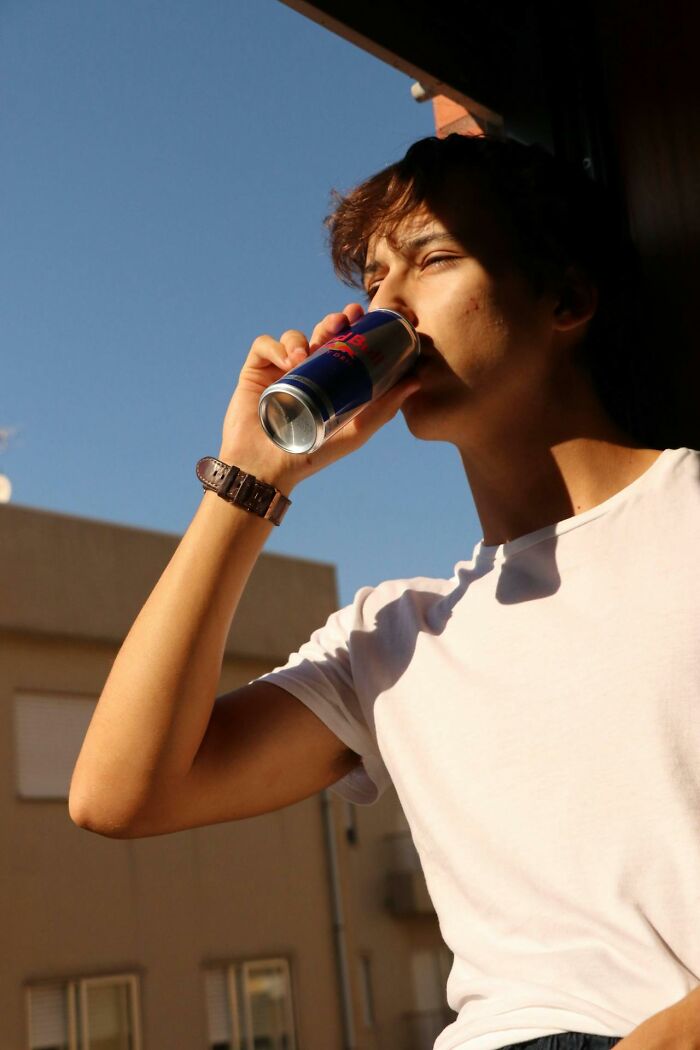Young man drinking energy drink outdoors for boneheaded comments