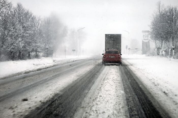 Snow-covered road with cars driving carefully through winter conditions