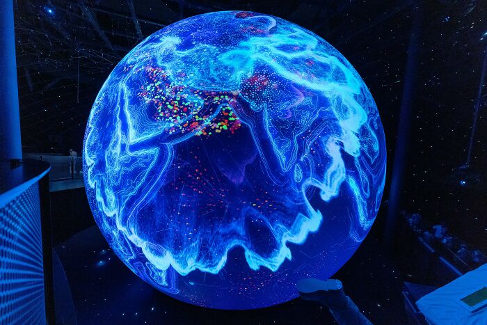 Glowing digital globe displaying global data points in a science-themed interactive exhibit