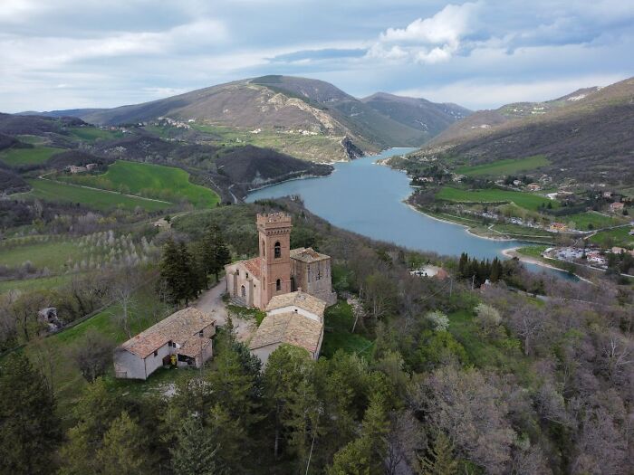 Aerial view of scenic landscape with church near lake and surrounding hills