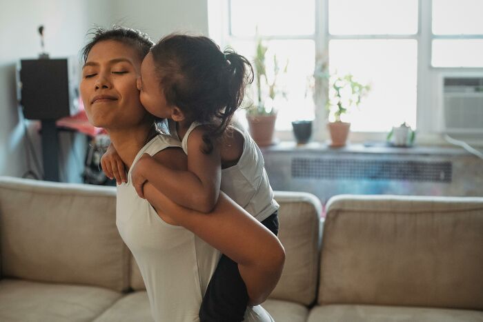 Young child giving mother a kiss on the cheek at home