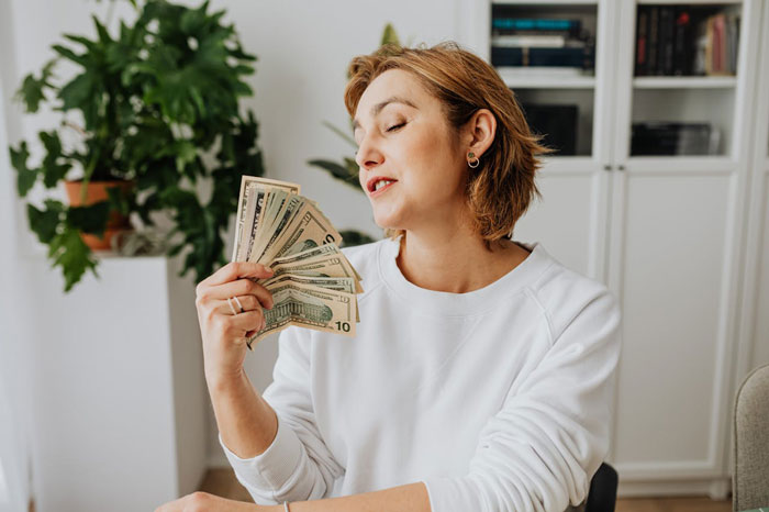 Woman holding fan of cash symbolizing inheritance or money Woman holding fan of cash symbolizing inheritance or money