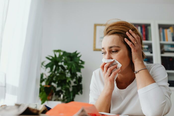 Woman laughing with tissue in hand in cozy home setting