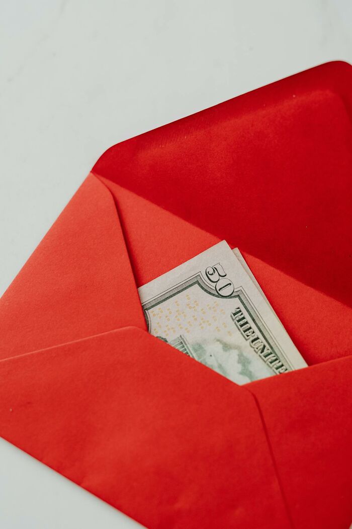 A red envelope holds a fifty-dollar bill, symbolizing financial transactions, secrets, or immoral acts that change how people see someone.