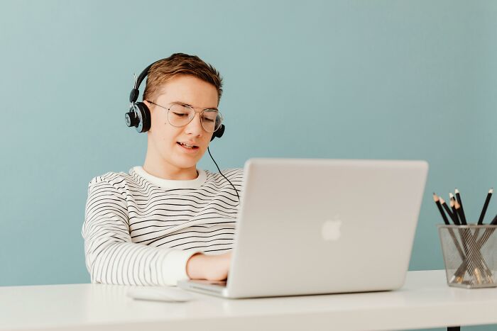 Young man with glasses and headphones focused on a laptop. Perfect for learning difficult famous quotes and grammar.