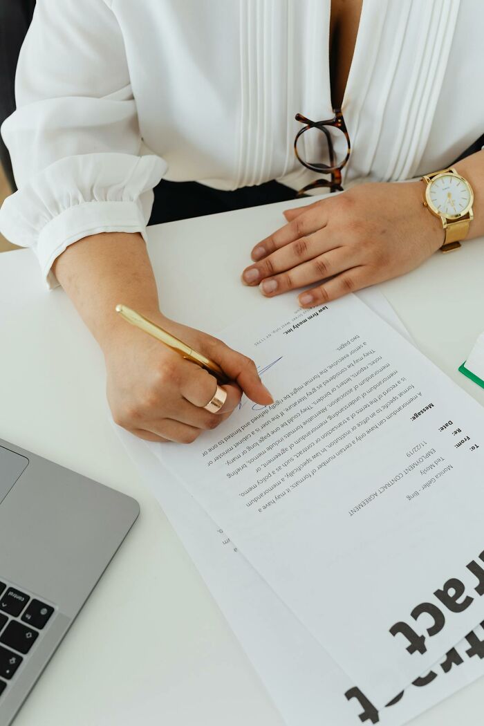 Person signing a document wearing white blouse for boneheaded comments