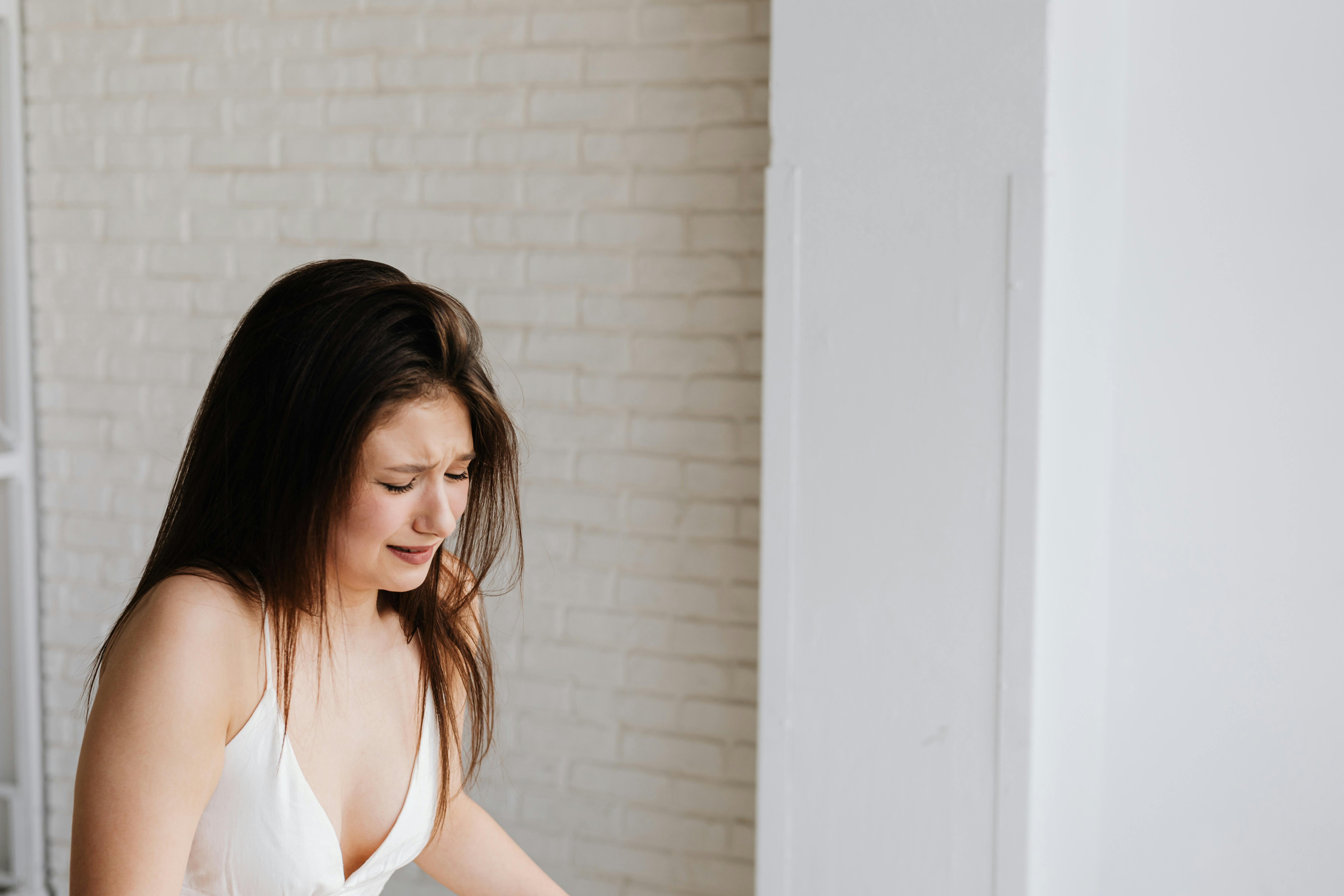 Cryng woman in white dress experiencing emotional wedding distress