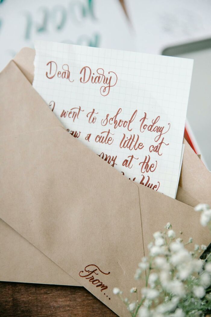 Handwritten diary note partially inside a brown envelope on wooden surface