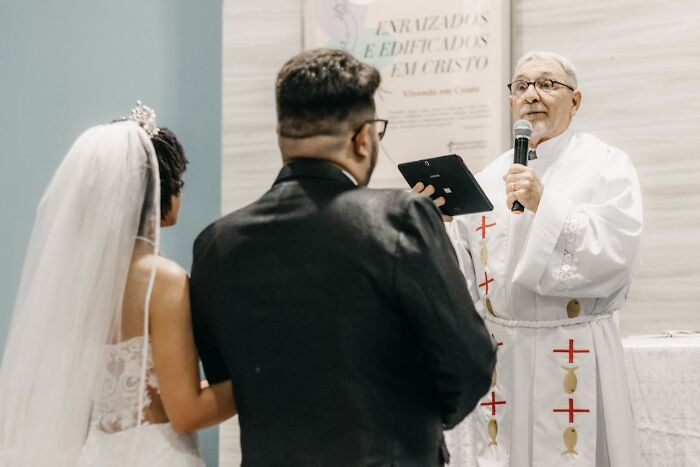 Bride and groom at wedding ceremony with priest officiating vows