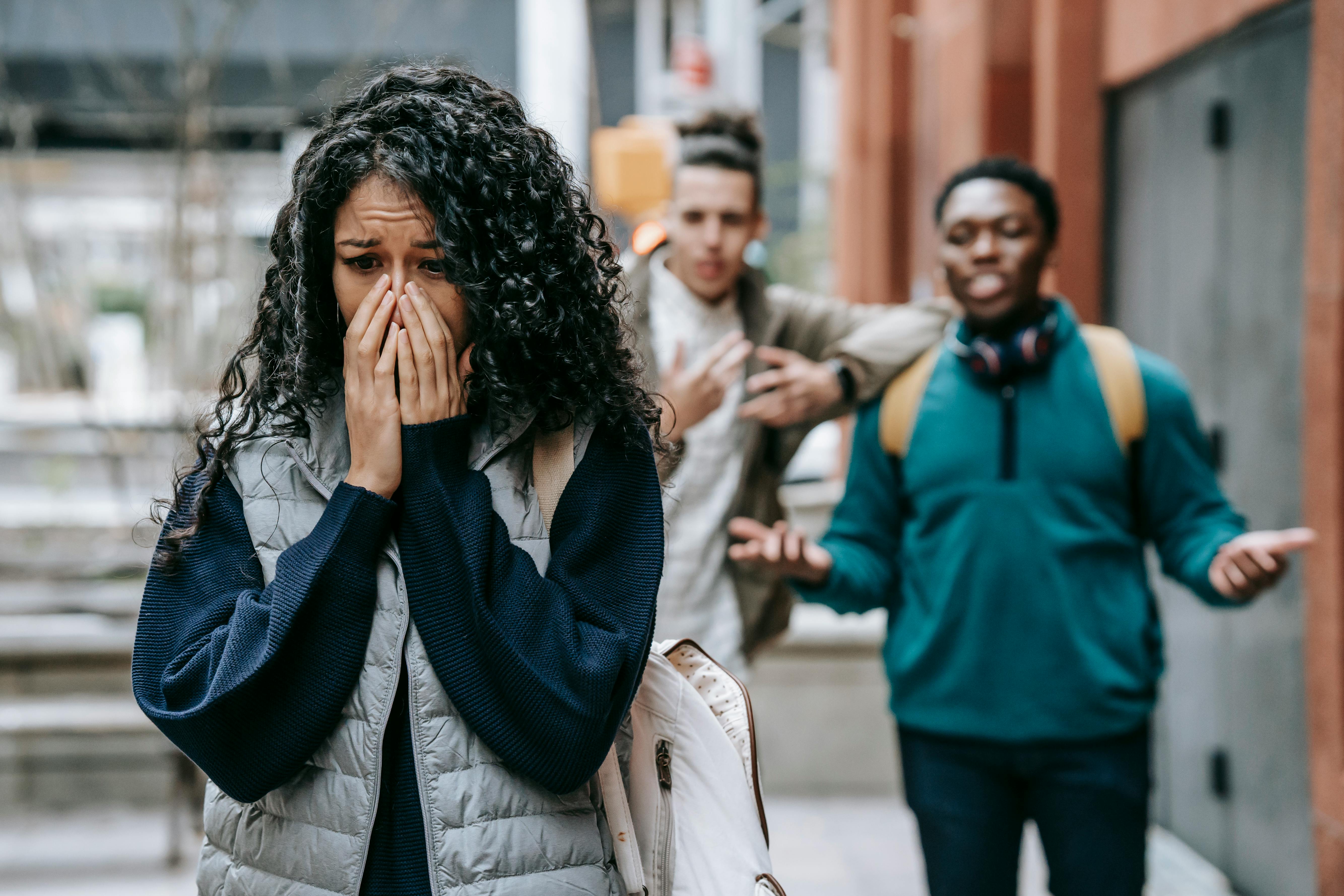 Woman upset being mocked by men on street illustrating emotional distress