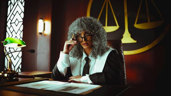 Judge with gray wig and glasses at courtroom desk