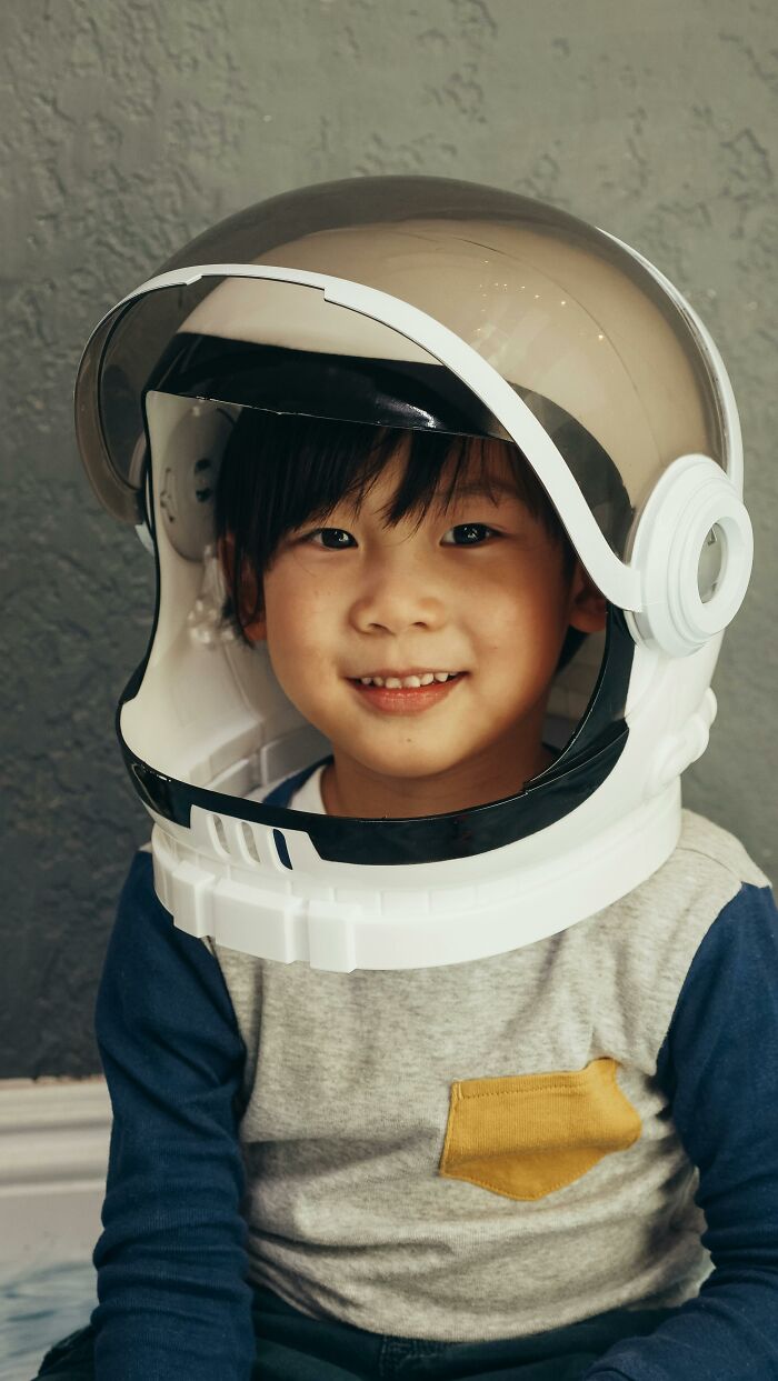 Young boy wearing astronaut helmet smiling at camera