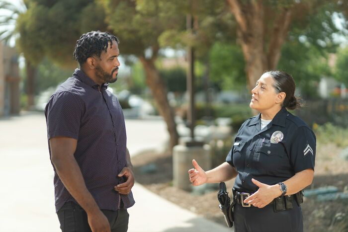 Police officer talking to man on neighborhood sidewalk
