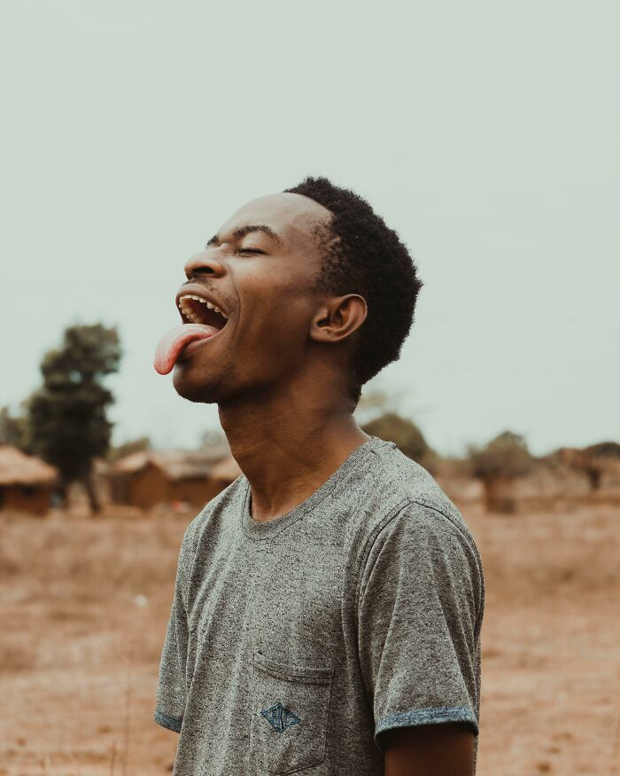 Man sticking out tongue outdoors in casual shirt
