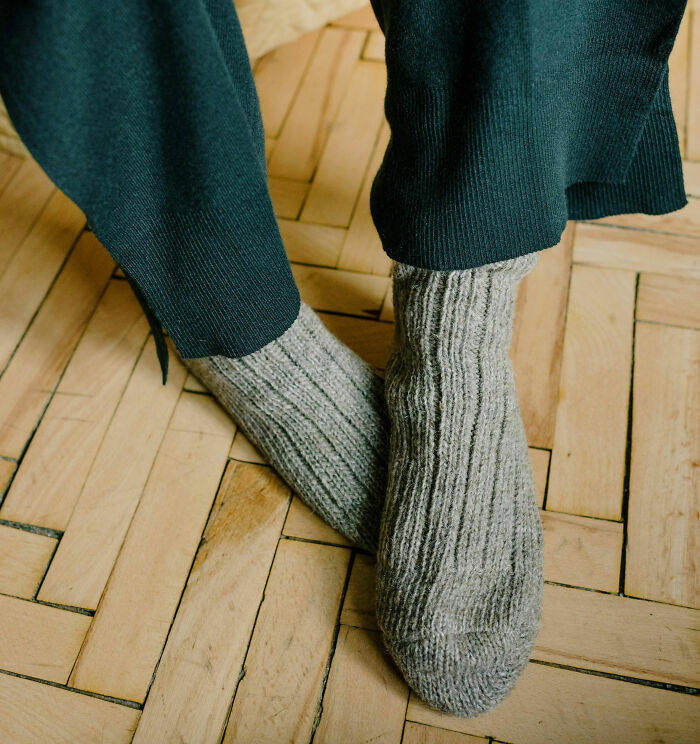 Close-up of feet wearing cozy wool socks on wooden floor