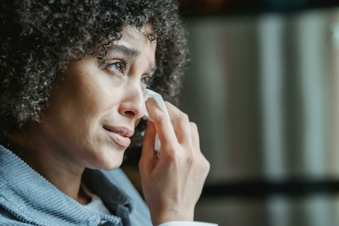 A woman with curly hair wipes her eyes, possibly reacting to creepy things she experienced.
