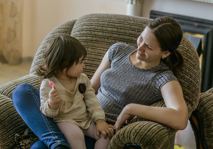 Mother talking and smiling with toddler on couch