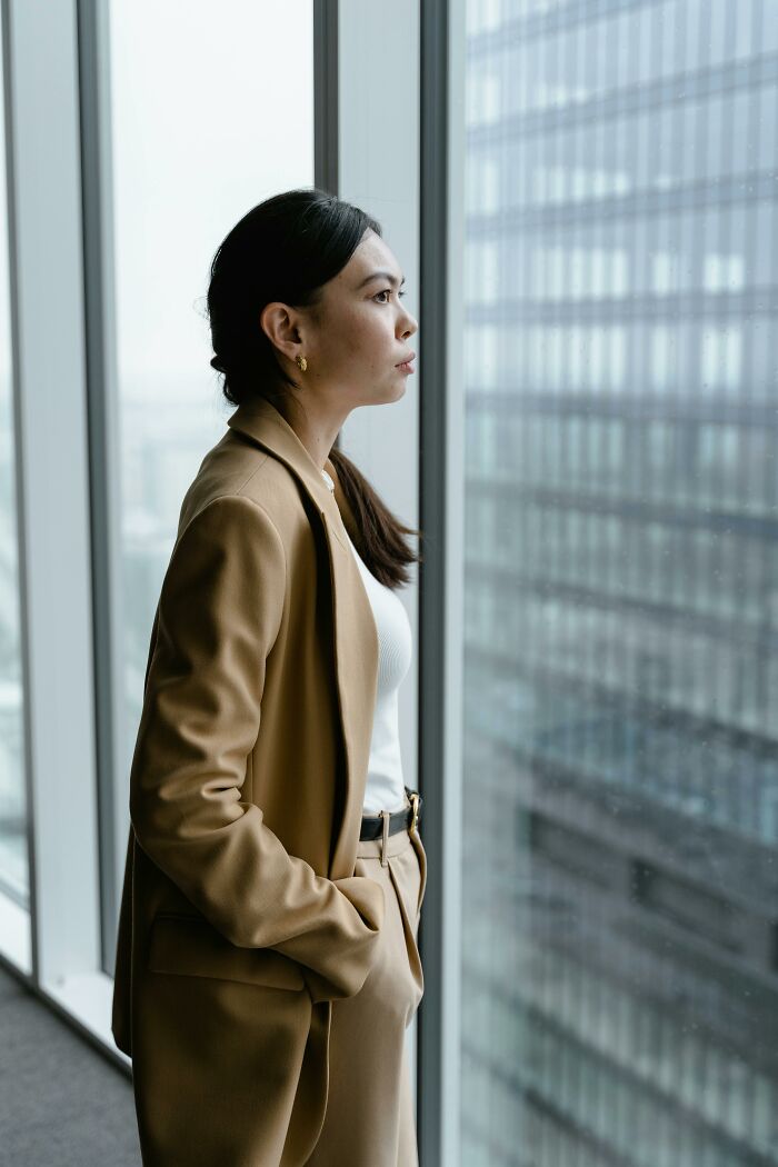 A woman in a tan suit looks pensively out a window at a city building. abortion supporters.