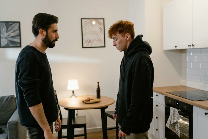 Young man and older man having a serious talk in a modest kitchen setting