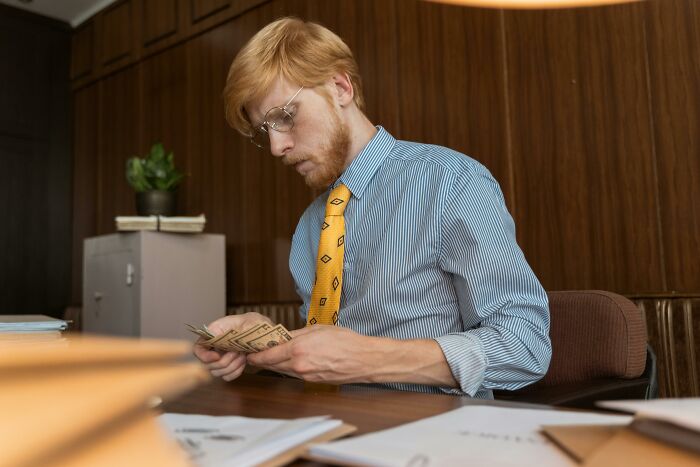 Businessman counting cash at desk highlighting financial considerations in quitting for peace