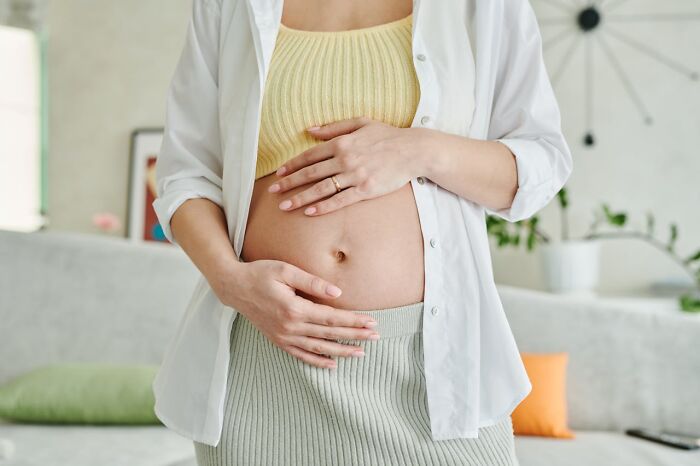 Pregnant woman touching belly in cozy home setting before wedding