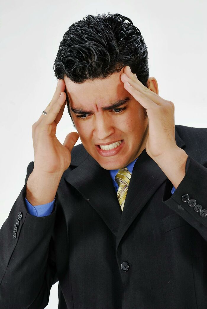 Stressed man in suit holding head, courtroom stories concept